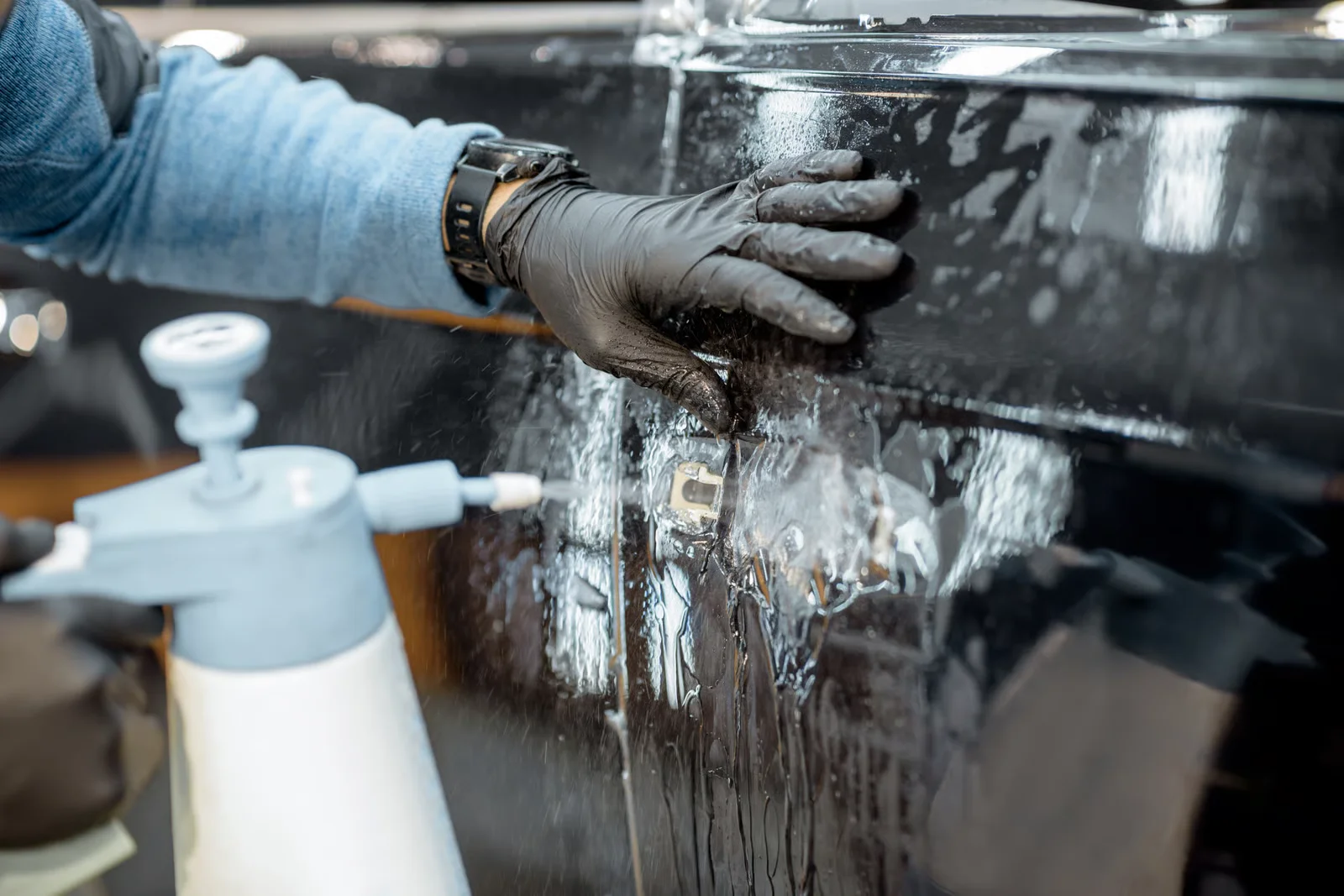 detailing specialist spraying decontaminant on a car's door