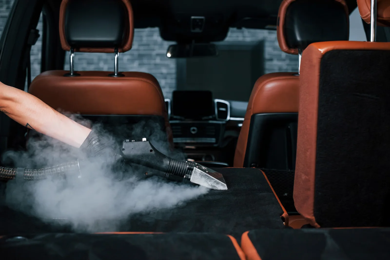 car detailing specialist steam vacuuming the carpets and interior of a vehicle