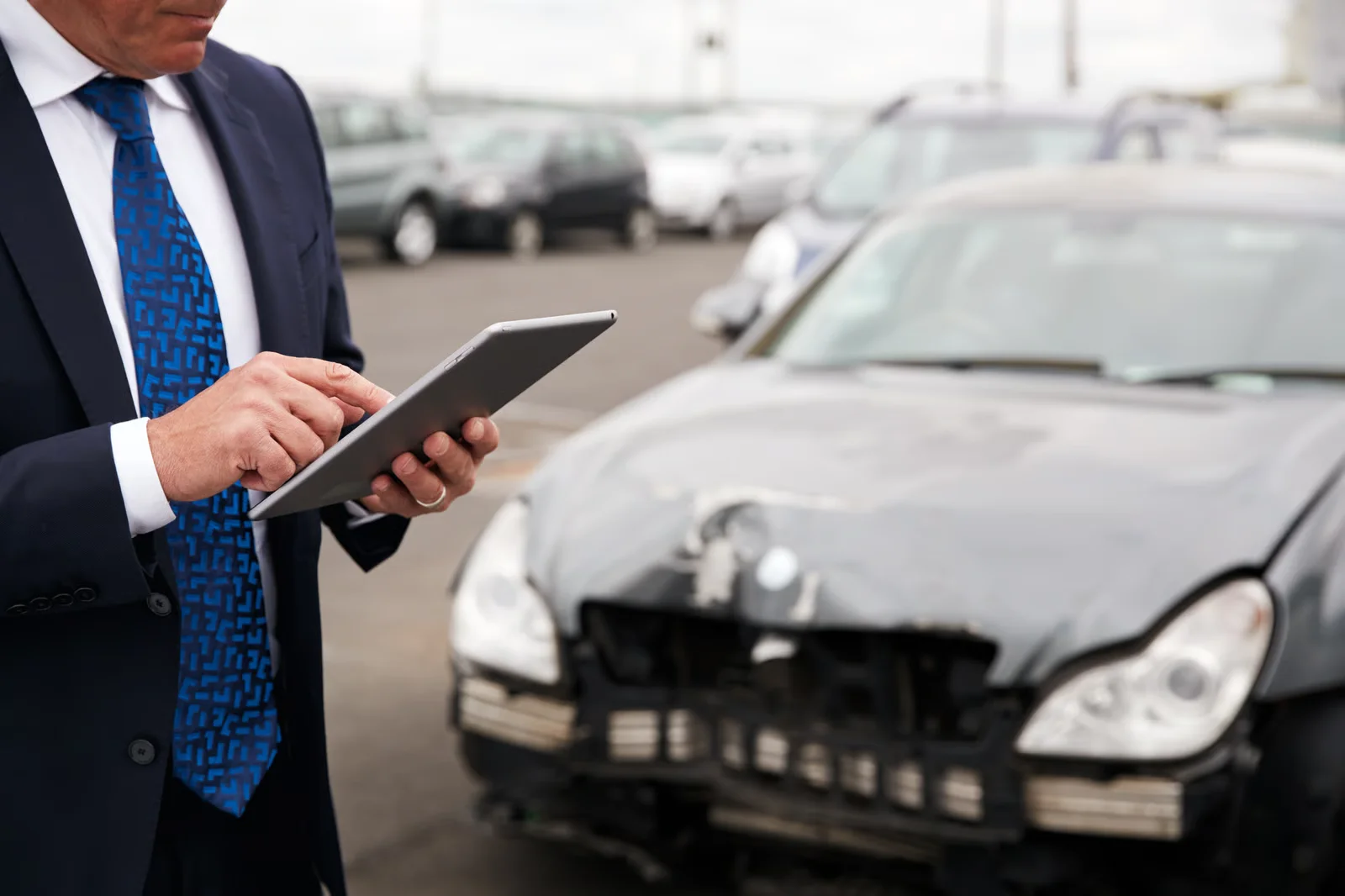 insurance adjuster inspecting damaged car using digital tablet