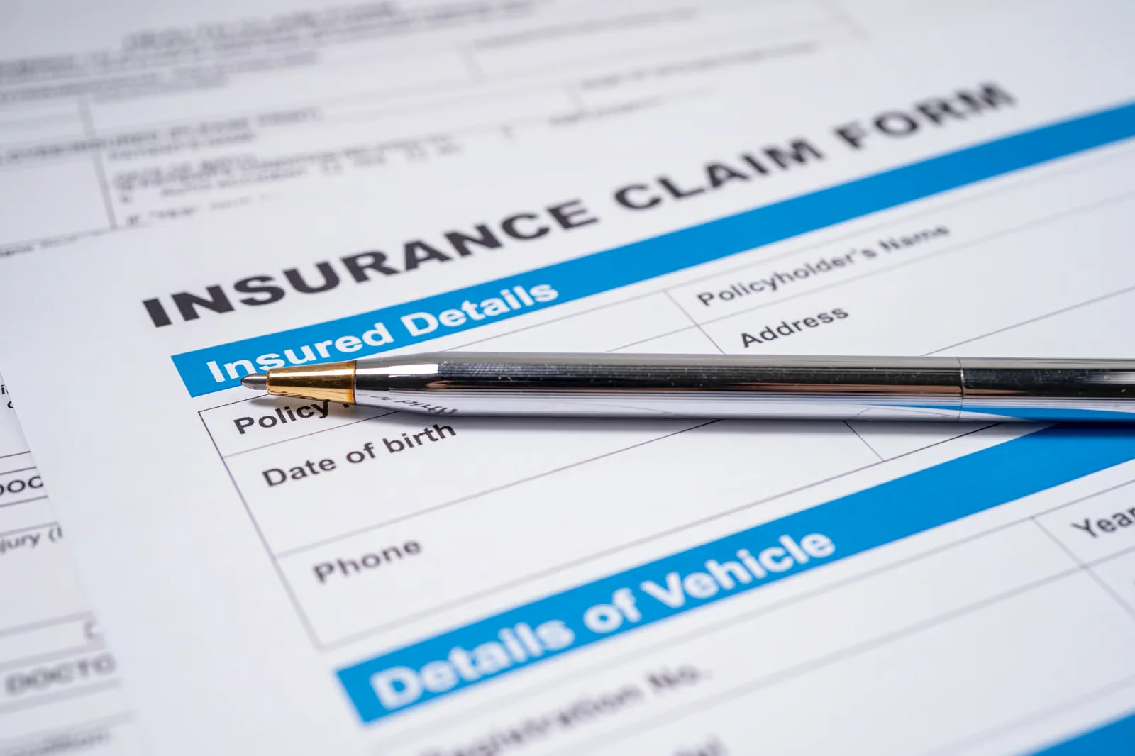 insurance claim form with a silver pen