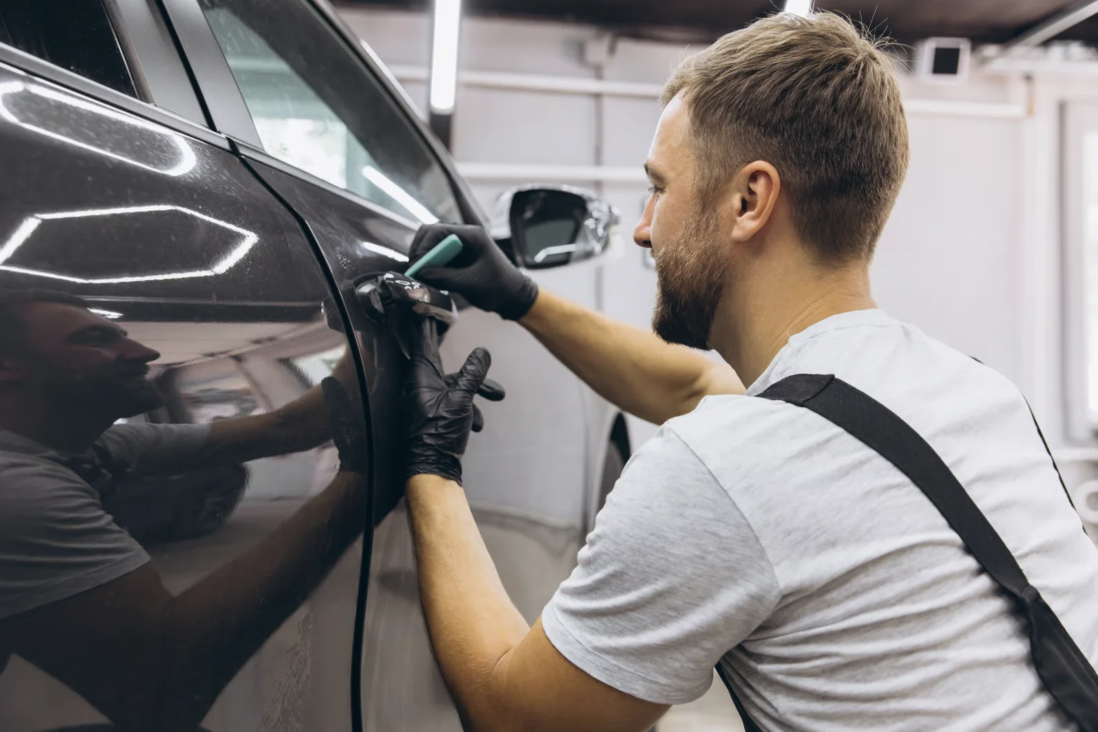 man detailing car in professional auto body shop