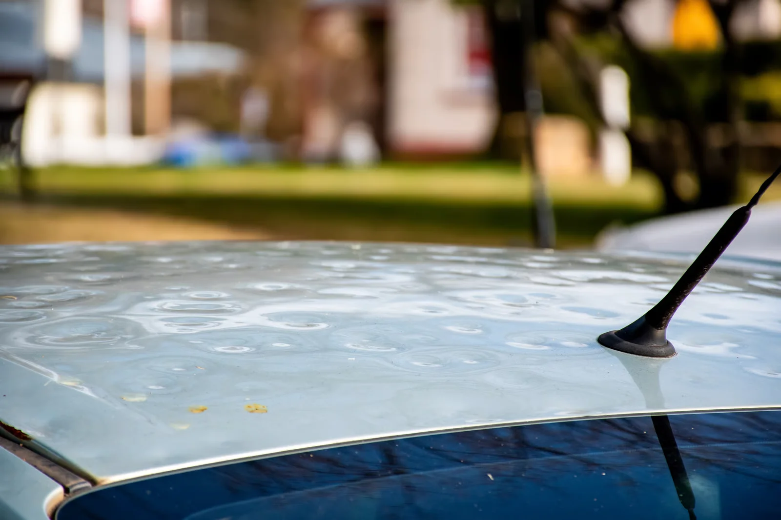 top of a light blue car covered in hail damage dents
