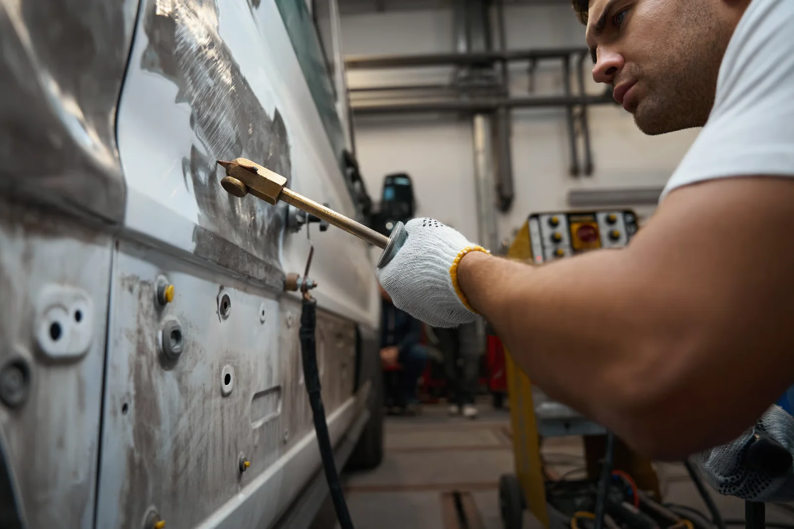 man repairing car with metal repair tool