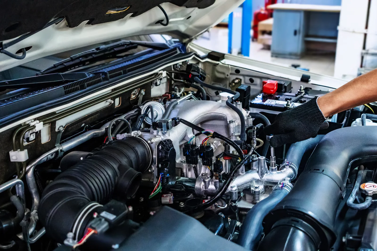 auto mechanic working with open car hood in garage. car repair service.