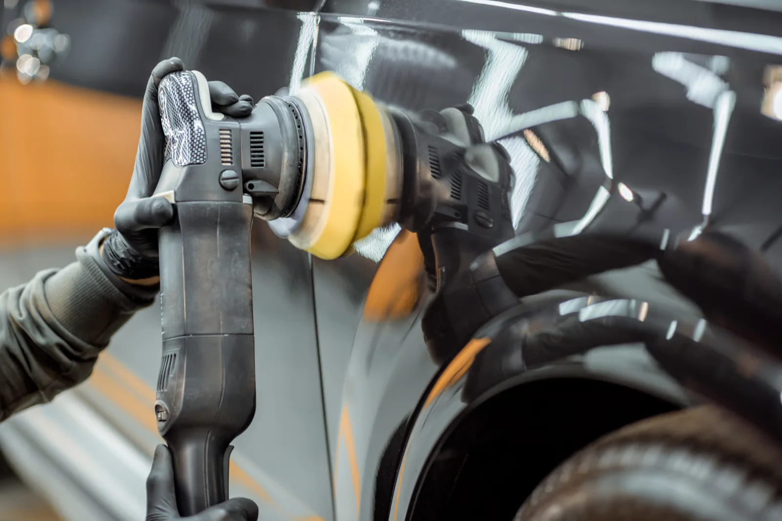 auto detailer using polisher on glossy car