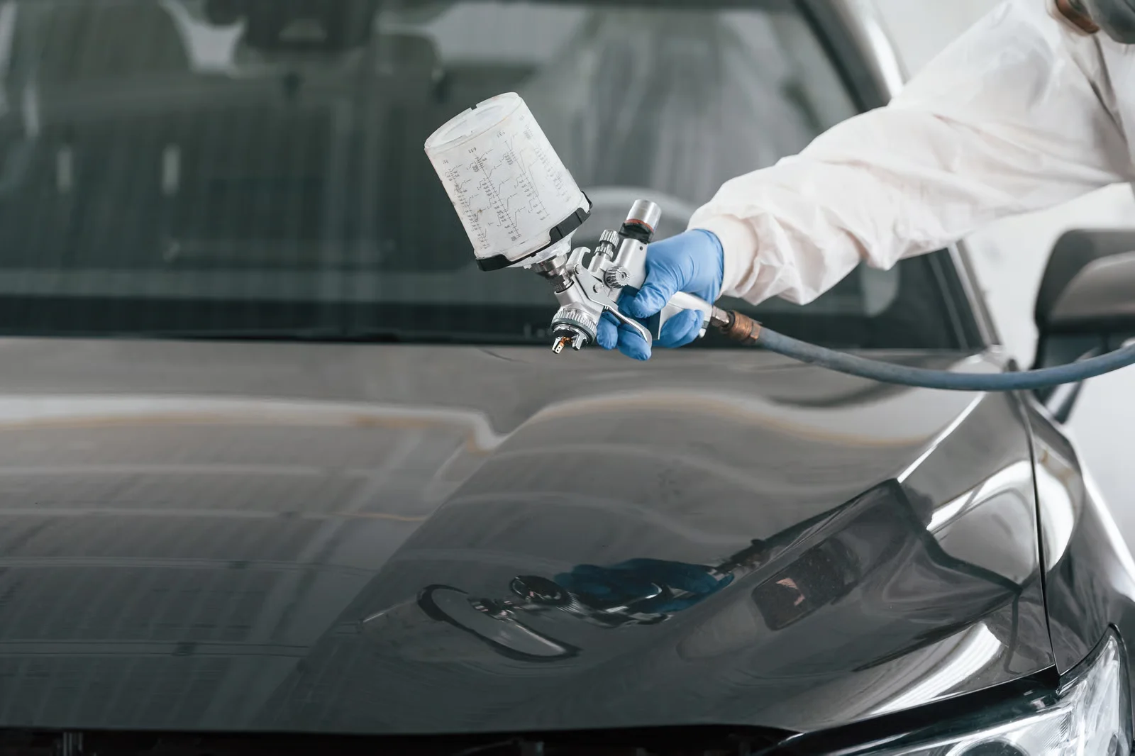 close up view of man that is painting a car by using spray guy
