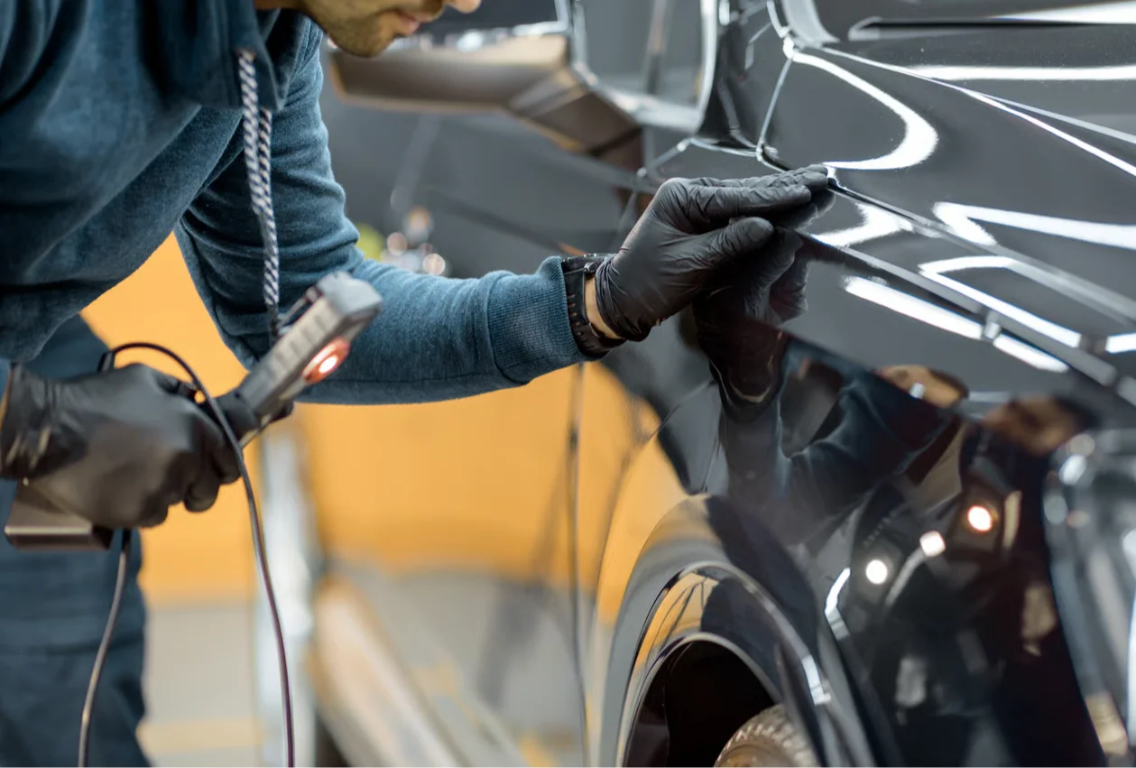 auto detailer inspecting car paint with inspection light