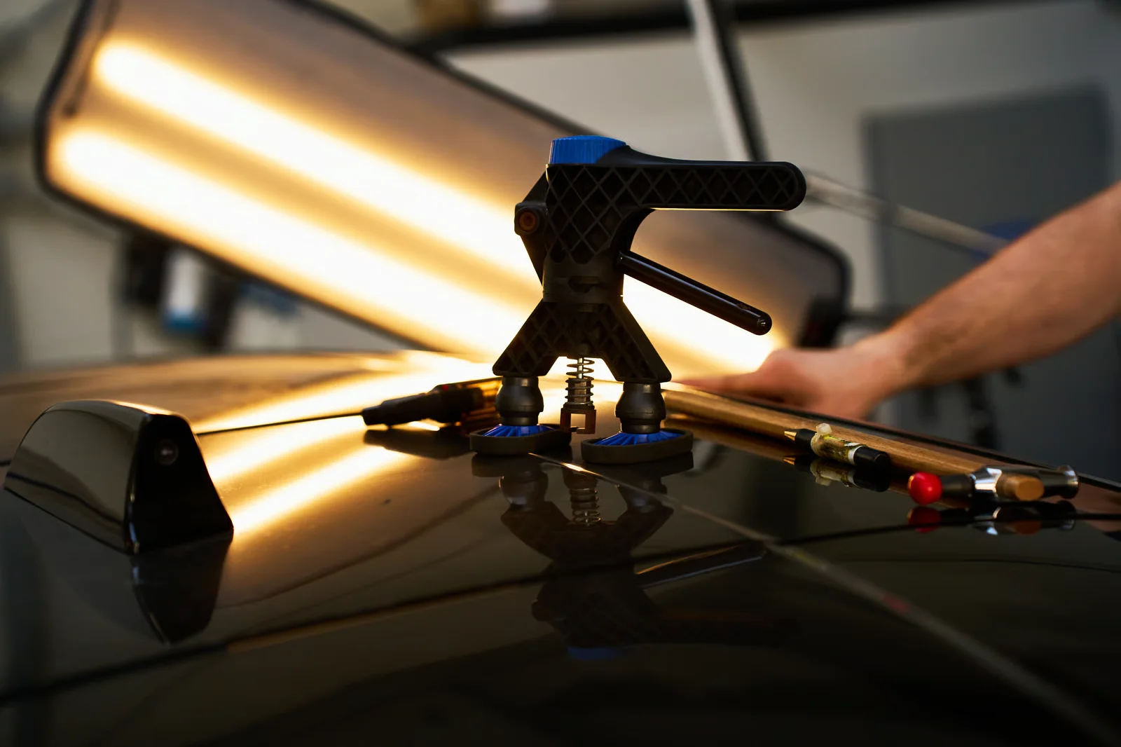 technician performing paintless dent repair on a black car