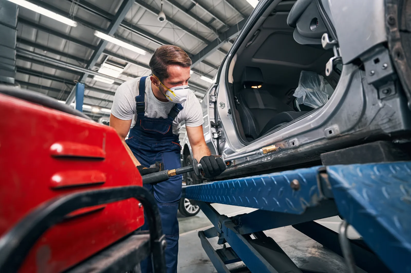 car mechanic working on car frame straightening in auto repair shop