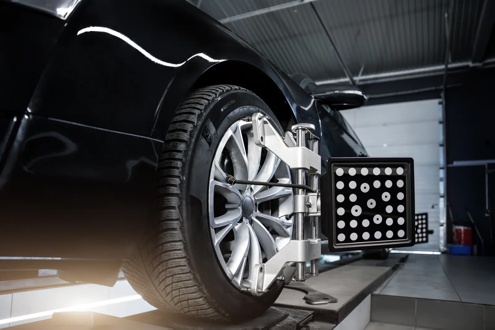 close-up car wheel indoors service maintenance repair center against laser sensor equipment