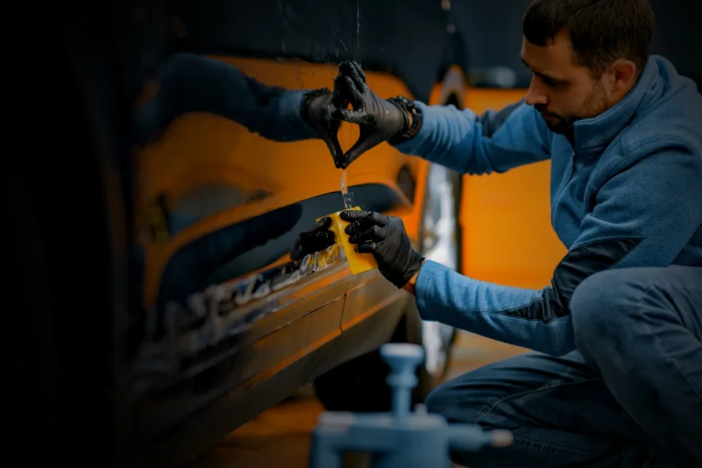 technician inspecting black luxury vehicle for scratches